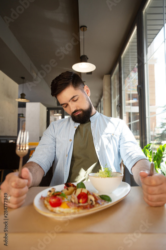 Sleepy bearded man wanting to eat in the restaurant