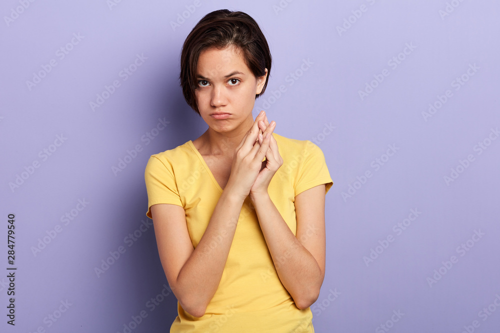Offended young woman keeps palms together. close up portrait, isolated blue background, studio shot. Offended young woman keeps palms together. close up portrait, isolated blue background, studio shot.