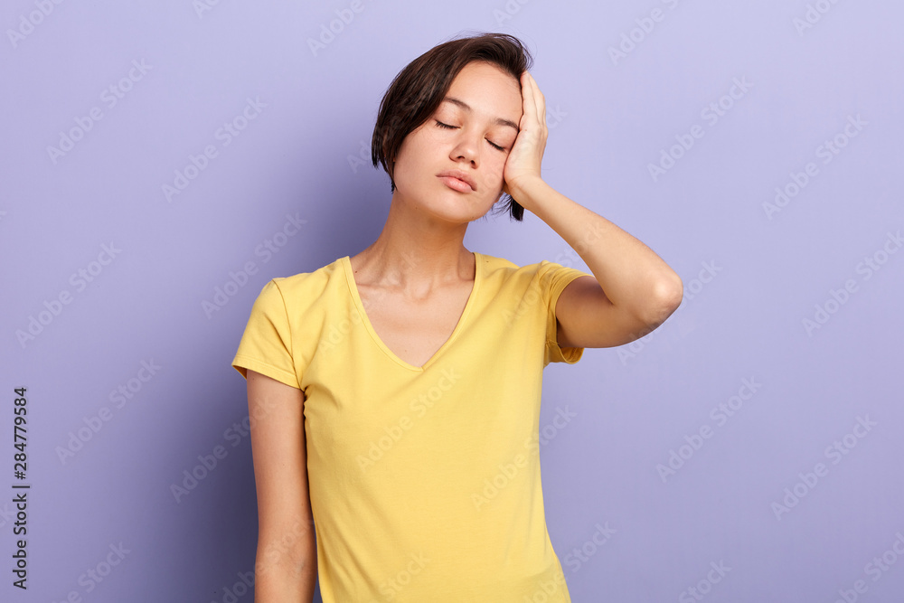 Tired woman with closed eyes suffering from headache.close up portrait, isolated blue background, studio shot. tiredness, depression, woman has problems with head Tired woman with closed eyes suffering from headache.close up portrait, isolated blue background, studio shot. tiredness, depression, woman has problems with head