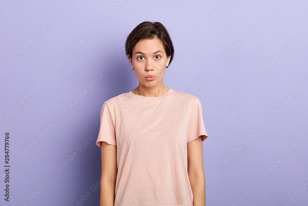 Closeup portrait of surprised young lady making moue with her lips isolated blue background, studio shot. facial expression. Closeup portrait of surprised young lady making moue with her lips isolated blue background, studio shot. facial expression.