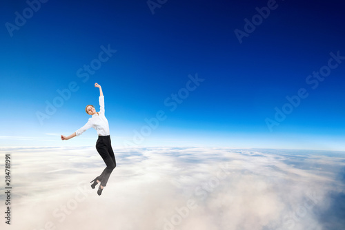 Businesswoman in formal wear flying in blue sky.