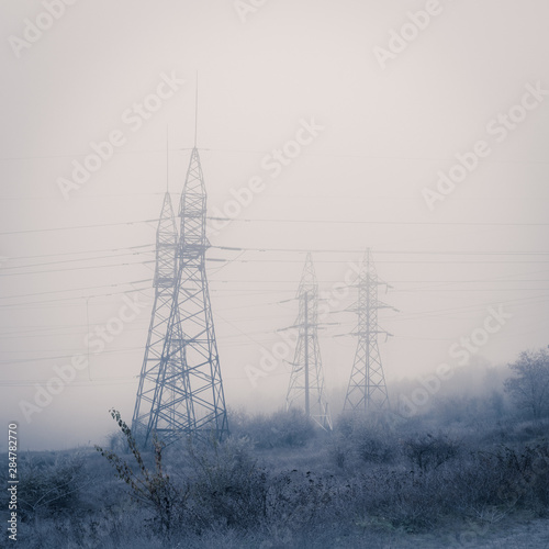 Electricity pillar and power lines on beautiful foggy day