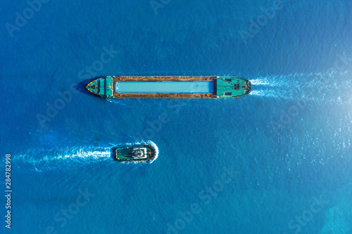 Fotografiet Cargo ship barge and tugboat sail to meet each other in the seaport of the port, aerial view