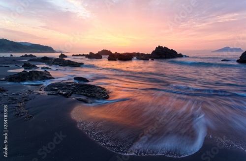 Sunrise scenery of a beautiful beach on Wai ao Coast  in Ilan   Yilan    Taiwan with golden sunlight reflecting on the water   sea waves rushing upon the shore in rosy twilight  Long Exposure Effect 