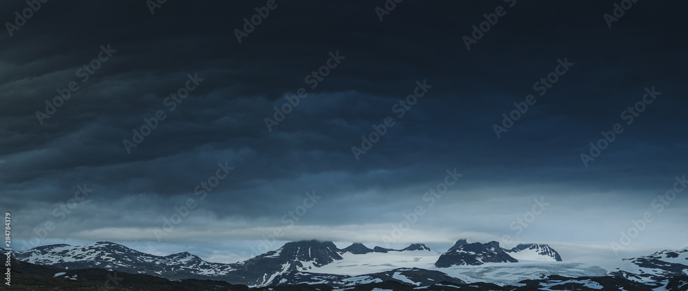 Panorama of gloomy cloudy Norwegeian mountains covered in snow, Norway