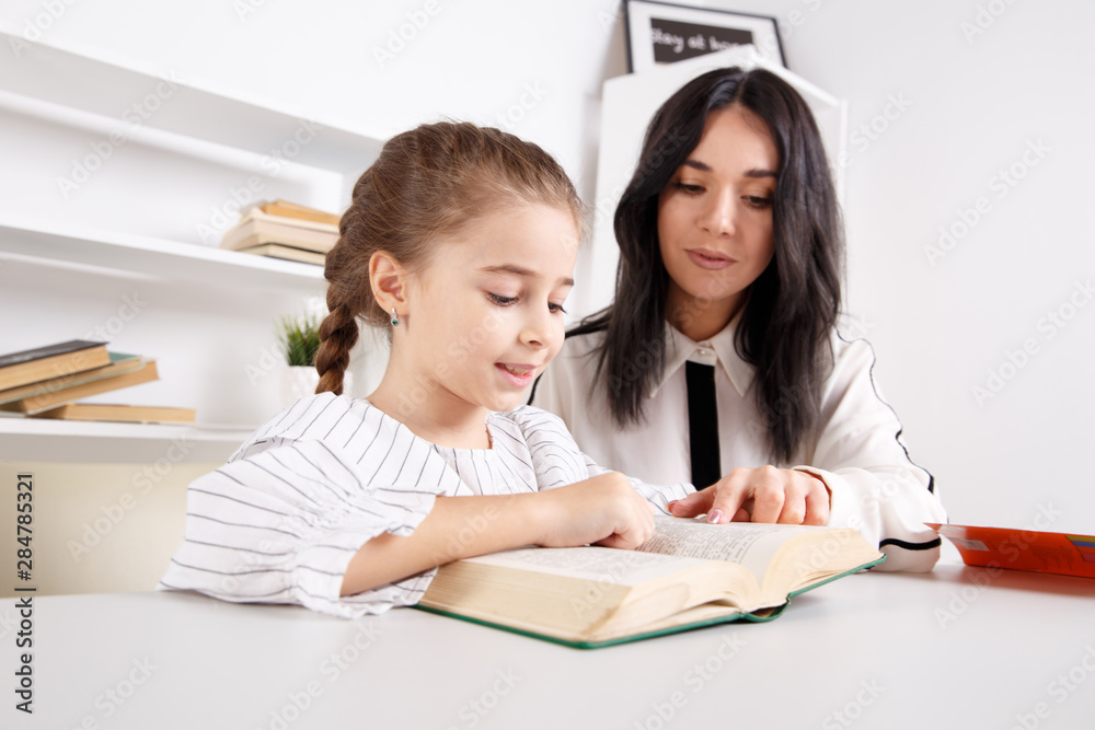 Mother and daughter reading sitting at home at the table Mother and daughter reading sitting at home at the table