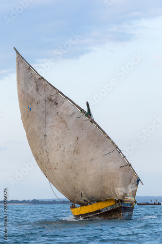 large african dhow vessel heading out to sea with a full lateen sail photo