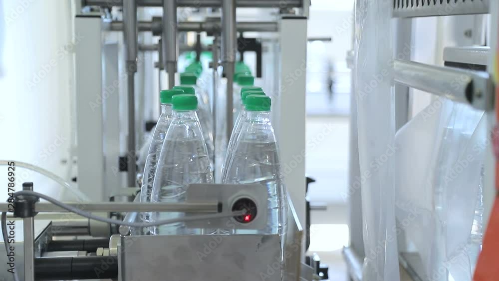 Automatic packaging of plastic bottles with film in the temperature press. Packaging of bottles for further transportation. Automatic packaging of plastic bottles with film in the temperature press. Packaging of bottles for further transportation.