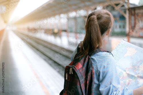 Young woman traveler holding map while looking for some direction at train station for travel. Travel concept by train..