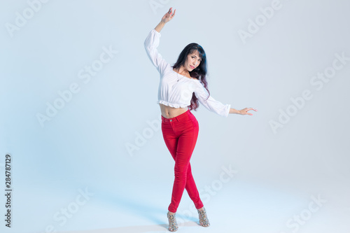 Latin dance, contemporary dance, bachata solo and cha-cha-cha concept - portrait of a young woman salsa dancer in a dance pose on blue background with copy space