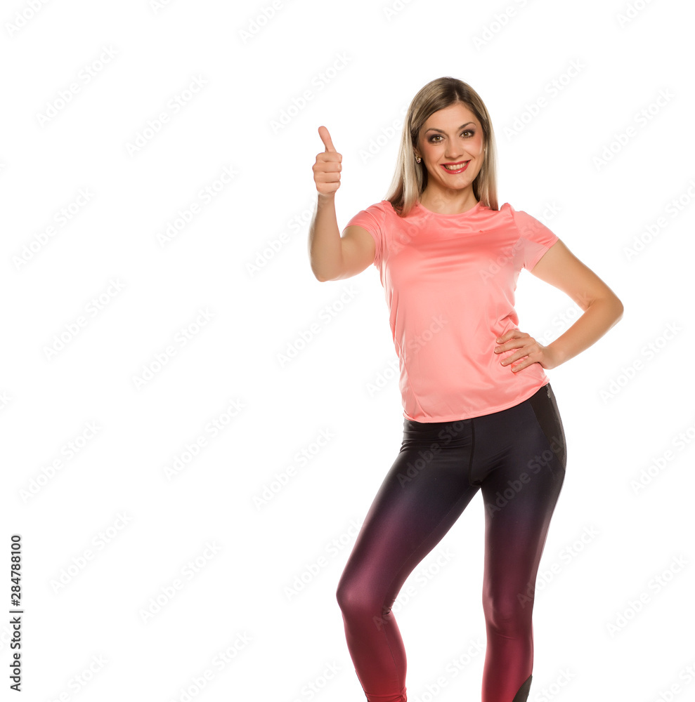 Young sporty woman posing with thumbs up on white background Young sporty woman posing with thumbs up on white background