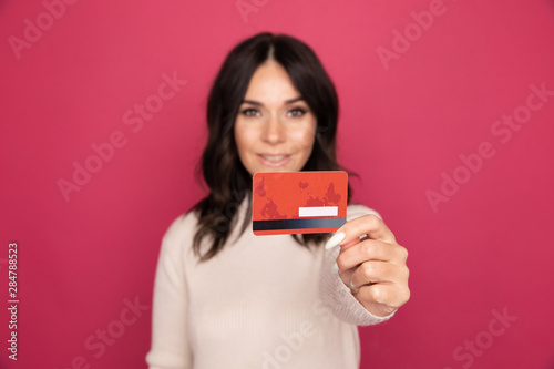Happy woman with credit card isolated in the pink studio