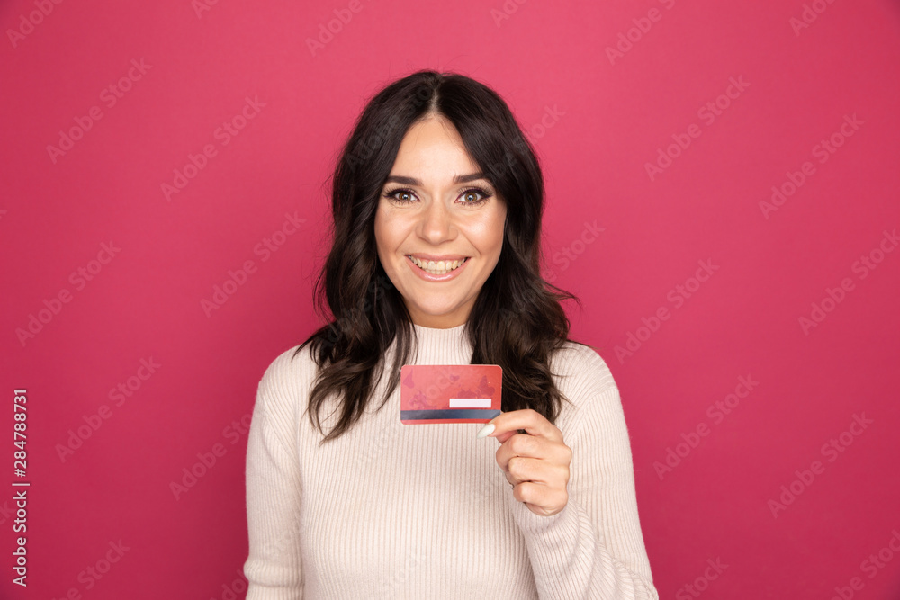 Happy smiling woman holding credit card isolated on the pink background Happy smiling woman holding credit card isolated on the pink background