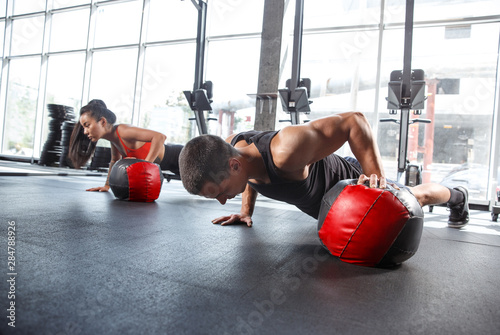 A muscular athletes doing workout at the gym. Gymnastics, training, fitness workout flexibility. Active and healthy lifestyle, youth, bodybuilding. Doing exercises together, training in push ups.