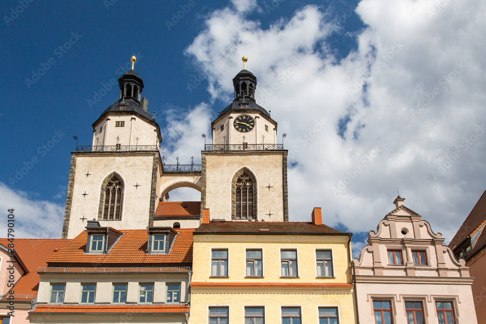 Lutherstadt Wittenberg, Details der Häuser am Kirchplatz sowie die Türme der Stadtkirche Wittenbergs vor Wolken und Himmel