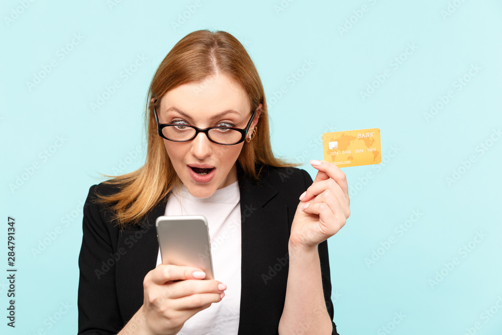 Sale online concept. Amazed woman with phone and credit card isolated Sale online concept. Amazed woman with phone and credit card isolated