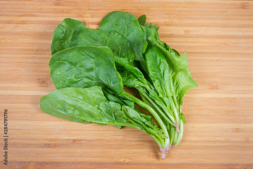 Stems with leaves of fresh spinach on a wooden surface Stems with leaves of fresh spinach on a wooden surface