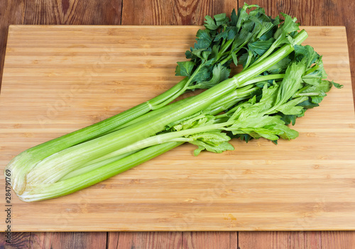 Fresh celery stalks on the cutting board on rustic table