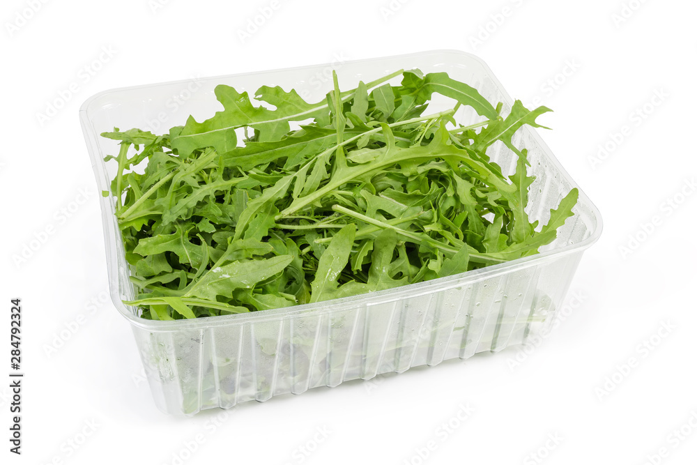Leaves of fresh arugula in plastic container on white background Leaves of fresh arugula in plastic container on white background