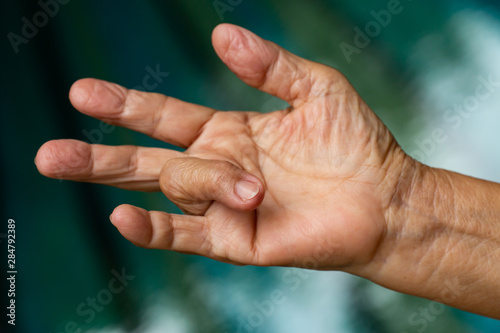 Trigger Finger lock on ring finger of senior woman's right hand, Suffering from pain, Swimming pool background, Health care concept