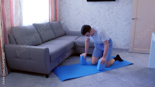 Crazy nerd man in glasses is trying to do the splits the first time on the mat at home and falling down. Sport humor concept.