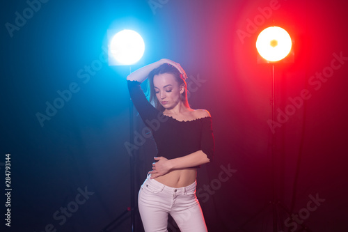 Dance, grace and elegance concept - young woman dancing bachata lady style in the dark, lights and smoke