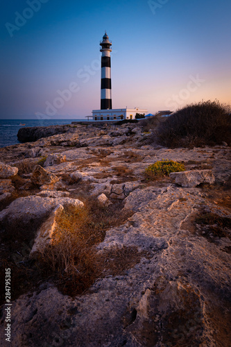 Blue hour view of the Cap Artrutx Lighthouse or Artrutx Lighthouse, an active 19th century lighthouse located on the low-lying headland of the same name on the Spanish island of Menorca.