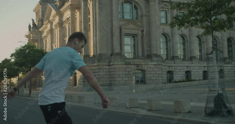 Handsome Europian man skating and doing cool tricks on roller skates in white blue t-shirt at city downtown location.Artistic improvisation of professional skating and spinning tricks.Camera following Handsome Europian man skating and doing cool tricks on roller skates in white blue t-shirt at city downtown location.Artistic improvisation of professional skating and spinning tricks.Camera following