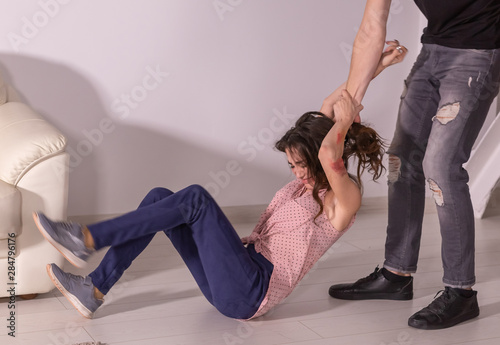 Domestic violence, abuse and victim concept - man and woman having fight, man dragging helpless woman by hair