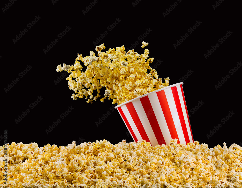 Flying popcorn from striped bucket isolated on black background