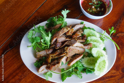 Special Thai Lao food (charcoal boiled pork neck and sticky rice) on wooden table.