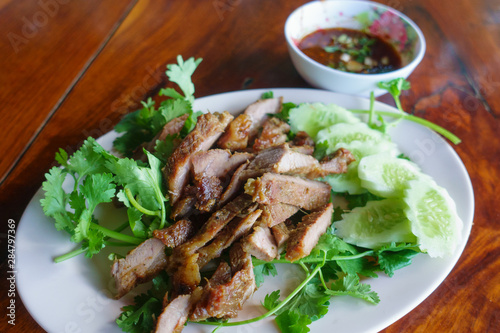 Special Thai Lao food (charcoal boiled pork neck and sticky rice) on wooden table.