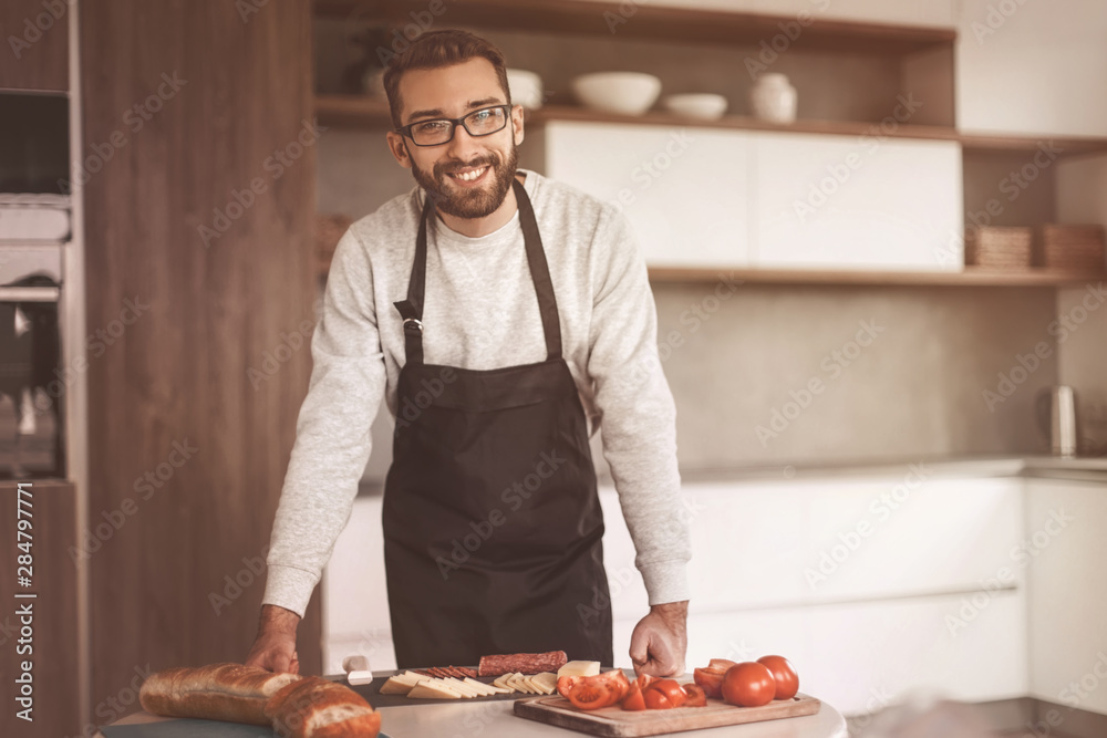 man in an apron slicing salami for sandwiches man in an apron slicing salami for sandwiches