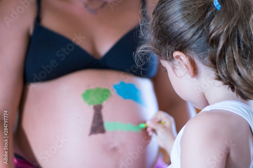 Niña pintando barriga de embarazada