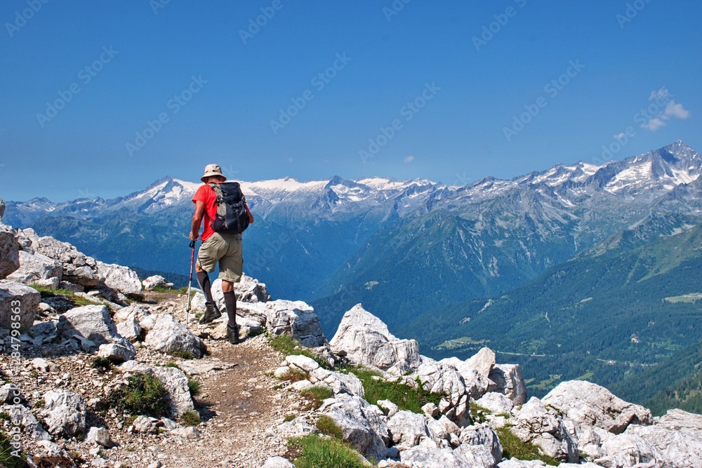 Senior hiker hiking in Brenta Dolomites, Italy with scenic rocky landscape in the background