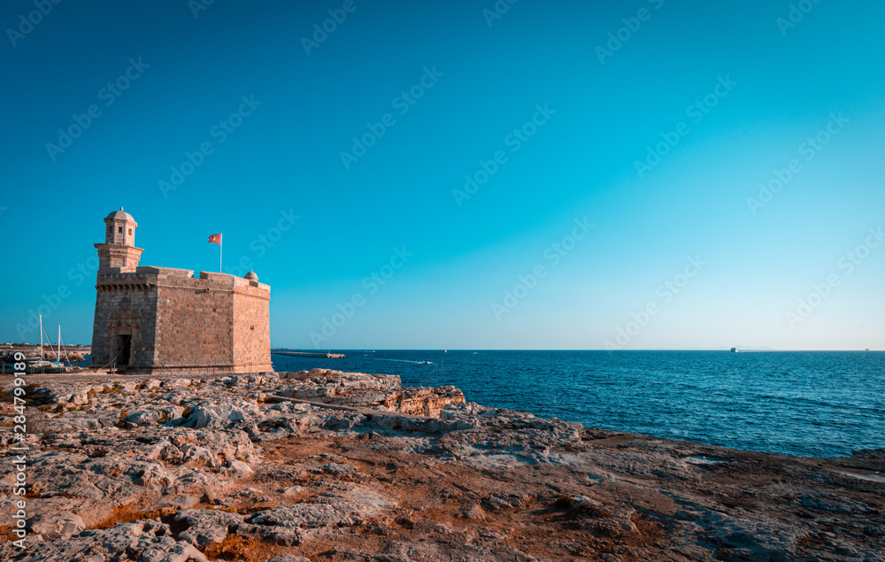 Teal and orange vief of Sant Nicolau Castle in beautiful mediterranean town of Ciutadella in Menorca island. The Sant Nicolau Castle is strategically located at the entrance of the Ciutadella port.