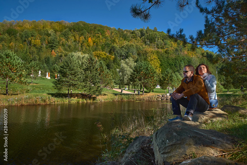 couple of tourists by the lake enjoy nature in a Buddhist temple in Quebec on a sunny day