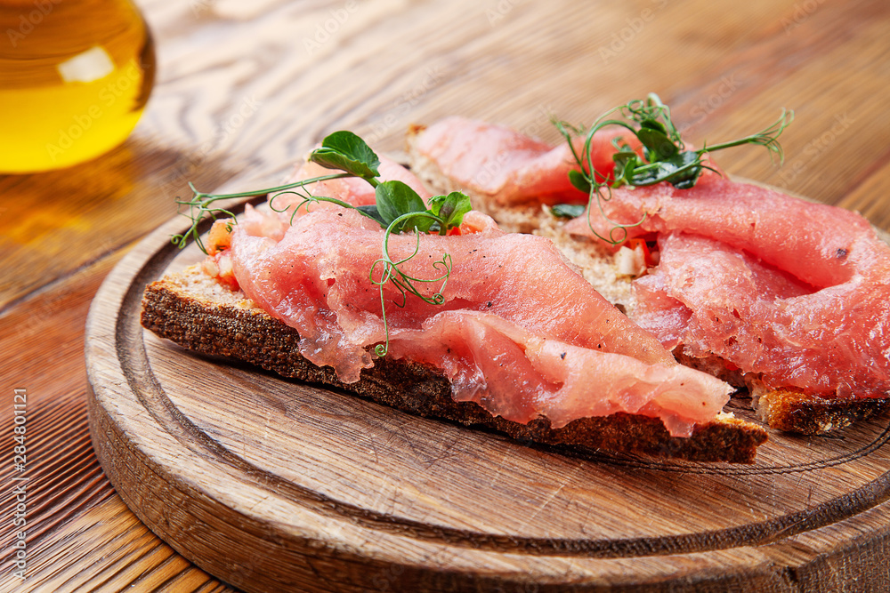 Delicious Bruschetta with tuna. Selective focus. Composition with Bruschetta and olive oil on wooden background. Bread with fish. Seafood. Food photo for menu. Homemade italian cuisine
