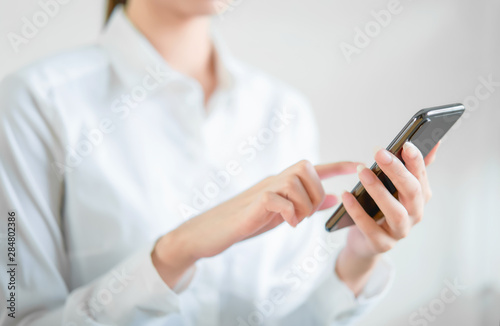 Close-up of hands using smartphone on wooden table and typing message to his friends.