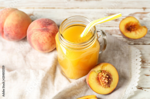 Mason jar of tasty peach juice on table