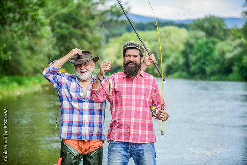 Fisherman with fishing rod. Activity and hobby. Fishing freshwater lake pond river. Bearded men catching fish. Mature man with friend fishing. Summer vacation. Happy cheerful people. Family time