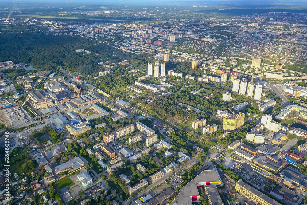 Panoramic aerial view of the city with tall buildings and a shopping center in the middle in Novosibirsk on a sunny afternoon at sunset. Industry and construction.