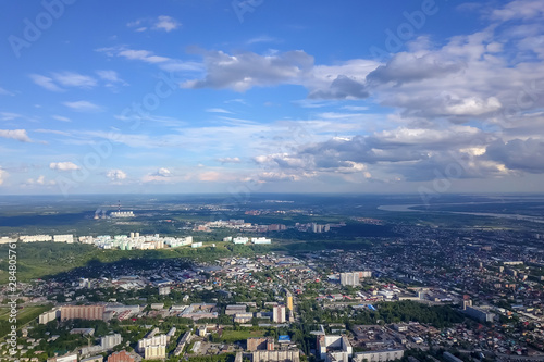 Aerial view of the cityscape with a lot of houses and buildings on a summer clear day under a blue sky with gray clouds in Novosibirsk.