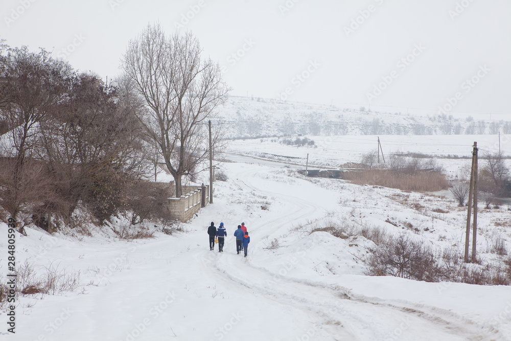 group of boys going on the snowy country road  