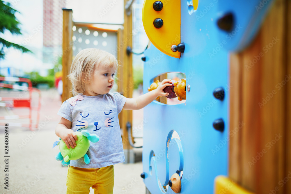 Fototapeta premium Adorable toddler girl having fun on playground