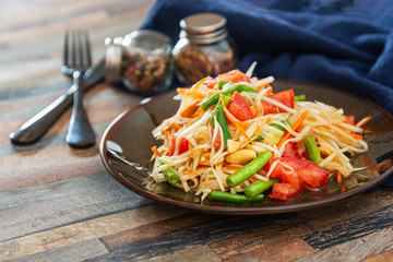 Traditional Thai food papaya salad prepared with fine slices of papaya, tomatoes, green beans and peanuts.
