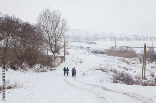 group of boys going on the snowy country road 