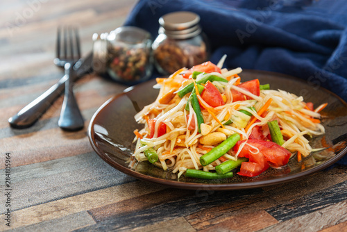 Traditional Thai food papaya salad prepared with fine slices of papaya, tomatoes, green beans and peanuts.