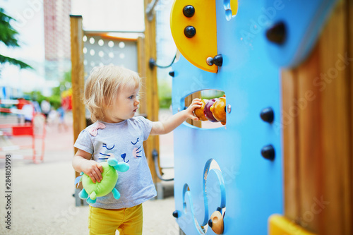 Adorable toddler girl having fun on playground