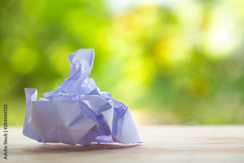 Crumpled white paper on wood table texture background in bokeh green garden background, Close up & Macro shot, Selective focus, Brainstorming, Creative idea, Business concept Crumpled white paper on wood table texture background in bokeh green garden background, Close up & Macro shot, Selective focus, Brainstorming, Creative idea, Business concept
